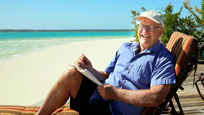 Roger Akelius i solstol på sandstrand