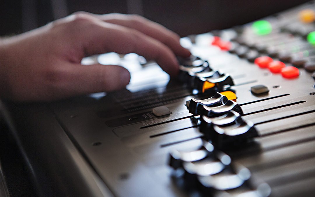 Hand som manövrerar ett mixerbord.