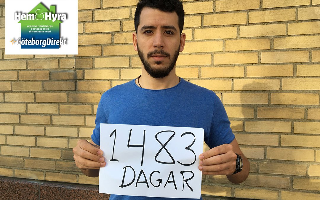 Jihad Eshmawi håller upp en textad skylt där det står "1 483 dagar" framför en husfasad.