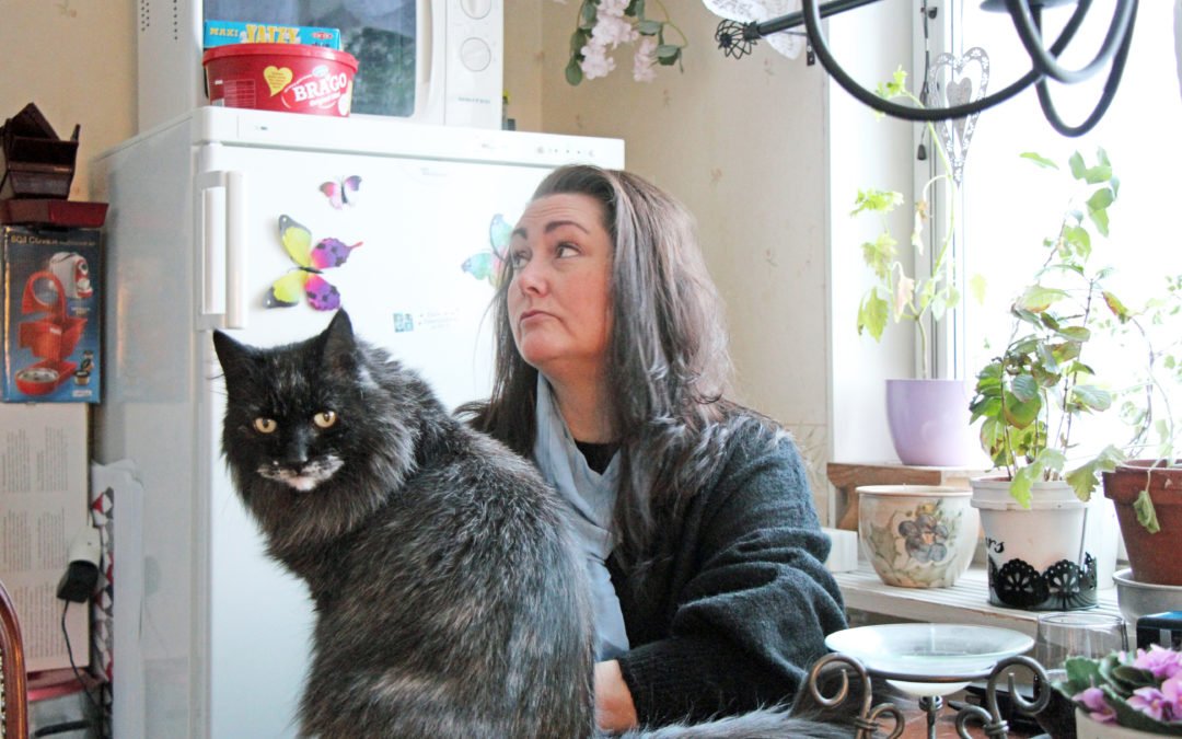 Petra Karlsson sitter vid sitt köksbord. På bordet sitter en katt.