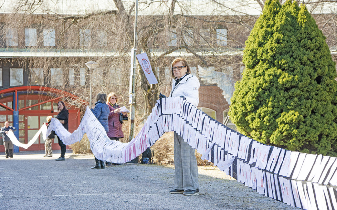 Bilden visar hur flera personer håller i den 60 meter långa gardinen. På gardinen är namnunderskrifterna fästade.