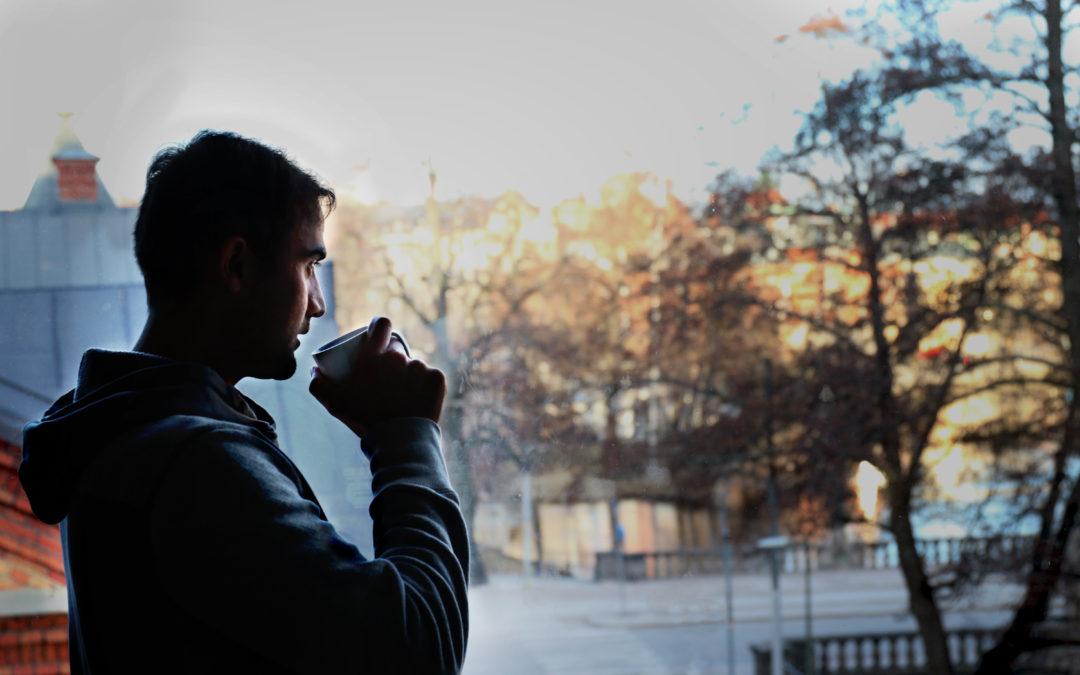 Farhad står med en kopp i handen och blickar från sin bostad ut på ett vintrigt Örebro.