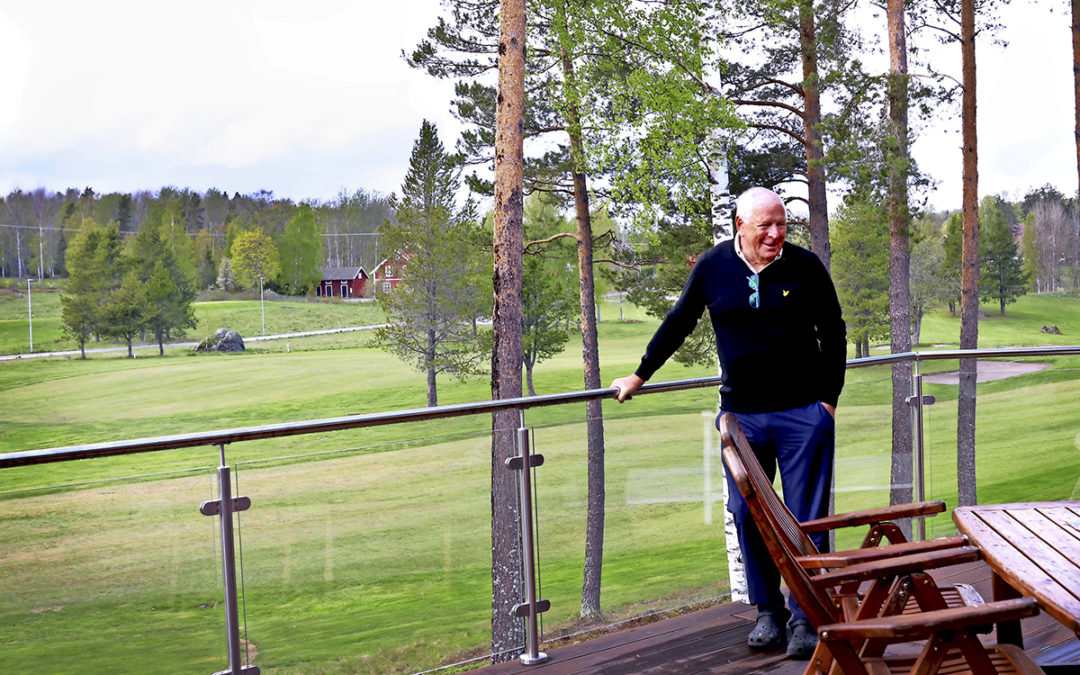 Kjell Guldbrand står lutad mot ett räcke. I bakgrunden syns golfbanan.