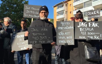 Svartklädda hyresgäster med plakat på Olskrokstorget.