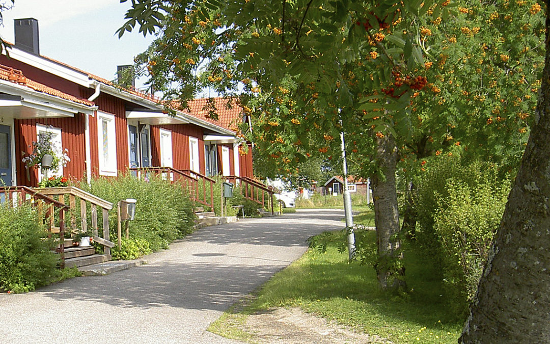 Röda längan i Järvsö. En huslänga i ett plan, rödmålad med vita fönsterfoder och blå dörrar. Till höger i bild ett rönnbärsträd.