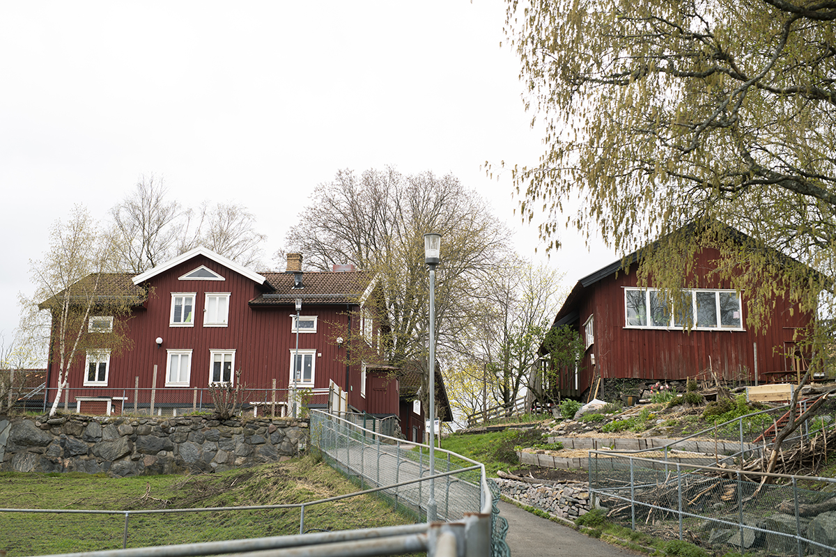 Lantgård. Rött hus med vita knutar.