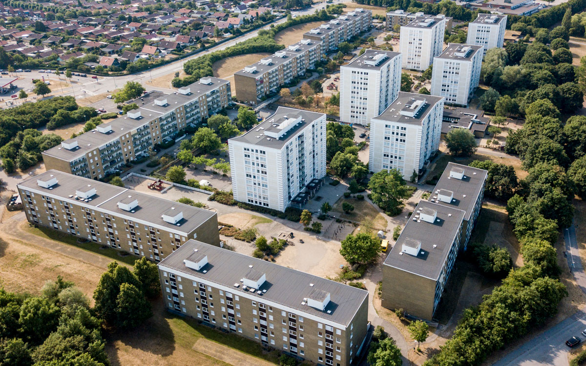 En flygbild över bostadsområdet Almgården i Malmö. På bilden syns sex vita höghus och sex lite lägre gulteglade flerfamiljshus.