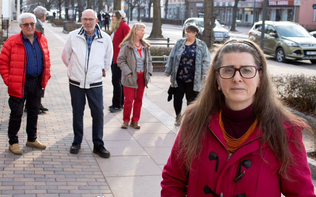 En kvinna står på en gata i Tranås. I bakgrunden syns en grupp andra kvinnor och män som samtalar med varandra. Kvinnan i förgrunden heter Angelica Engvall. Hon bär vinröd jacka och har glasögon och långt brunt hår.