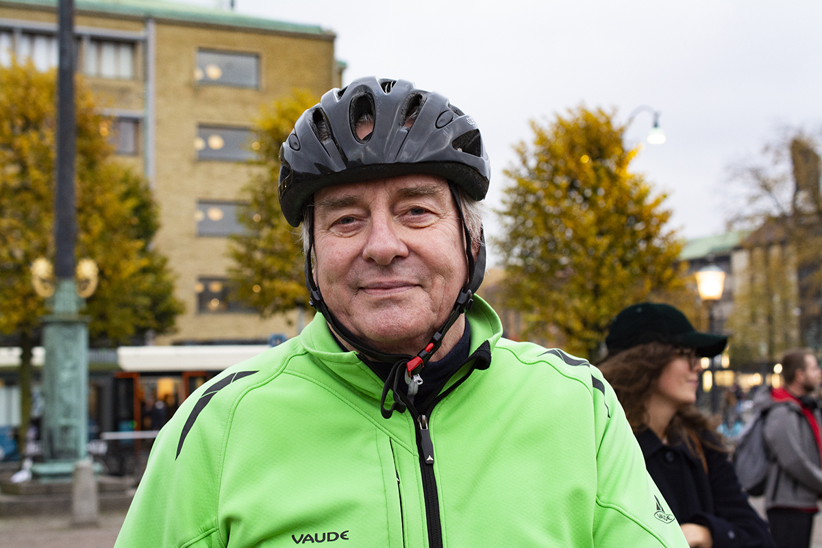 Krister Olander demonstrerar mot ombildningar av kommunala hyresrätter i Göteborg. Han är klädd i en neongrön jacka och cykelhjälm.