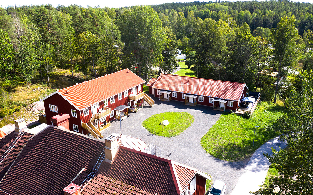 Hyreshus på landet. I det här fallet en drönarbild som visar hur Stavsjögården ser ut från luften. Man ser huskropparna med gårdsplanen i mitten.