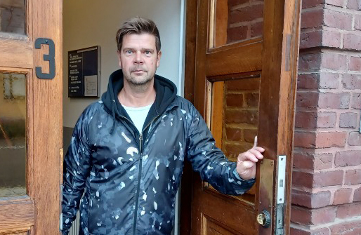 Hyresgäst Mikael Lundh i porten till huset där han betalat tusentals kronor för mycket i hyra.