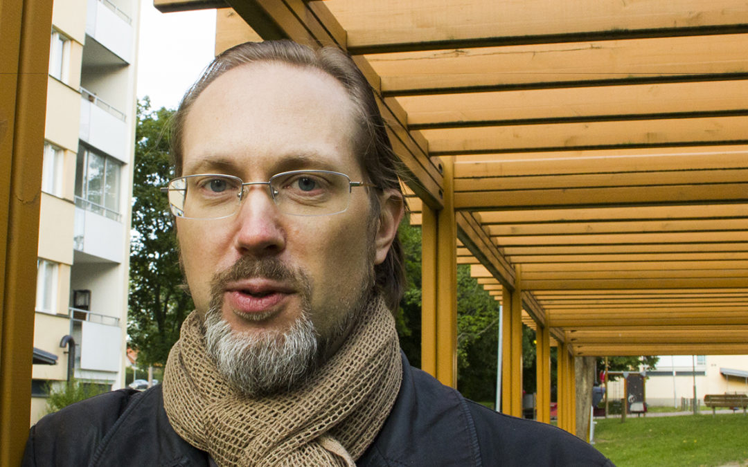 Michel Rowiński, porträttbild, i glasögon och halsduk. I bakgrunden till vänster syns ett höghus. Han står under en pergola. Michel har blivit suspenderad från sina förtroendeuppdrag i Hyresgästföreningen.