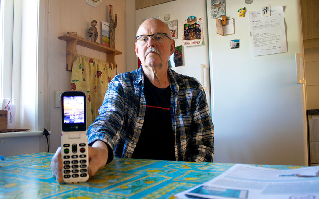 Man sitter vid ett bord och håller i en mobiltelefon