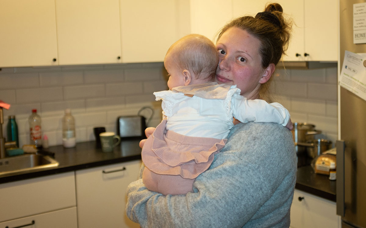 Kvinna med spädbarn i kök.