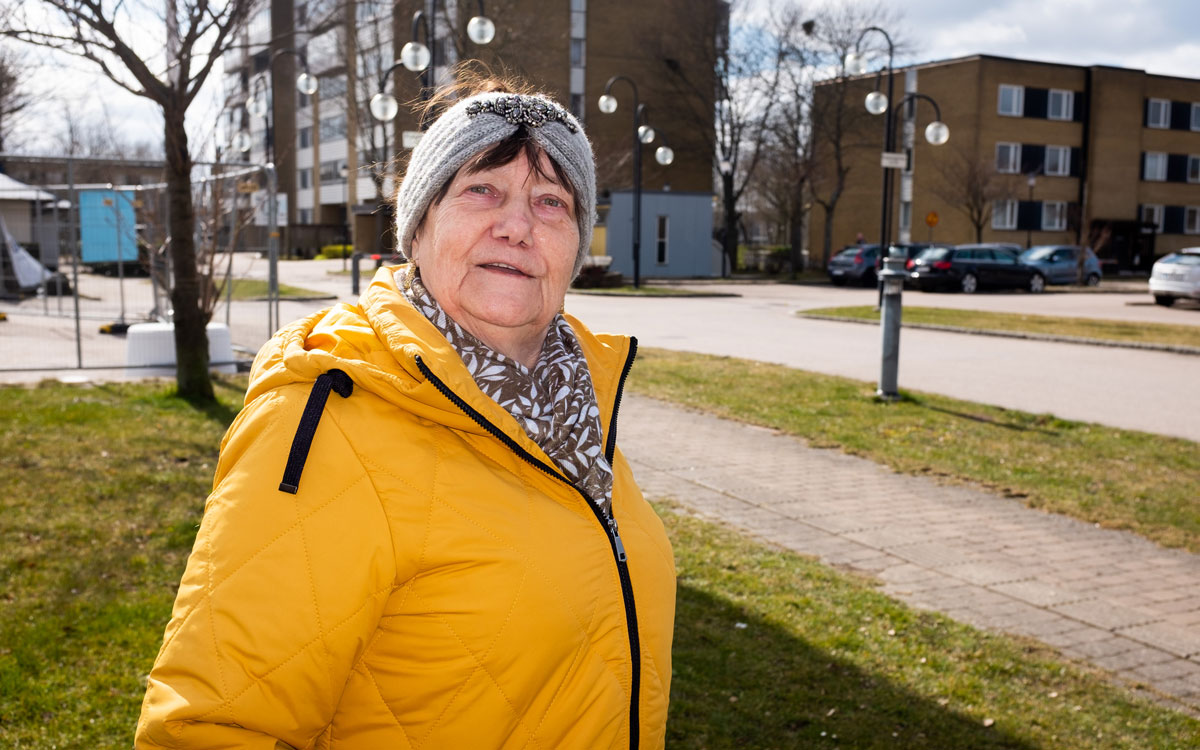 En kvinna i gul jacka i ett bostadsområde.