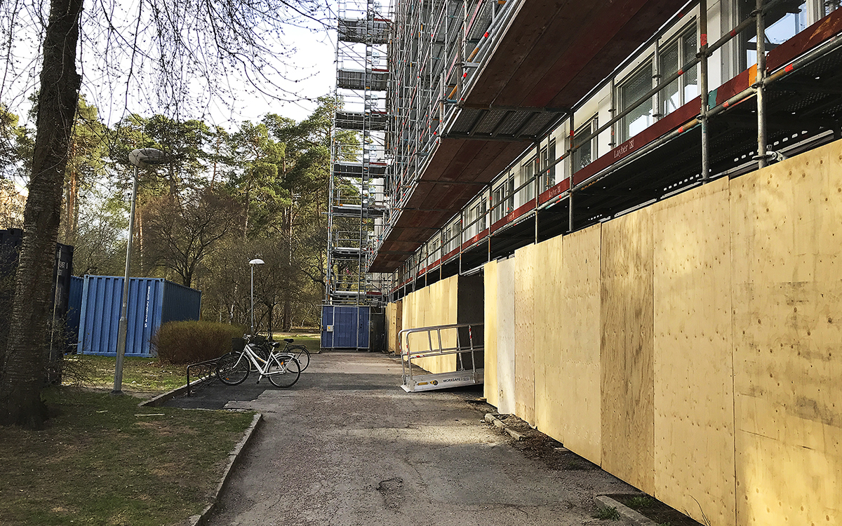 Renoverings på Granitvägen i Eriksberg i Uppsala, byggbuller, här ser man byggnadsställningen runt ett hus längs bottenvåningen. Till vänster och i bakgrunden höga träd.