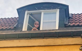 Fönsterbyte i Sala backe, fönsterkupa, hyresgästen Inga Bäckström tittar ut genom det öppna fönstret.