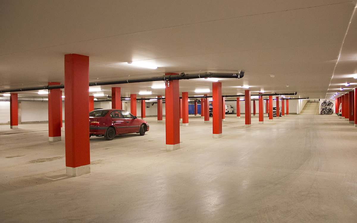 Många garageplatser står tomma samtidigt som folk felparkerar på gatan i kvarteret Senapsfabriken. På fotot parkeringen i källaren till huset, med stora tomma ytor, några få bilar och röda pelare.