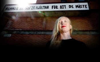 Gatukonstnären Jessica Hallbäck framför ett av sina verk