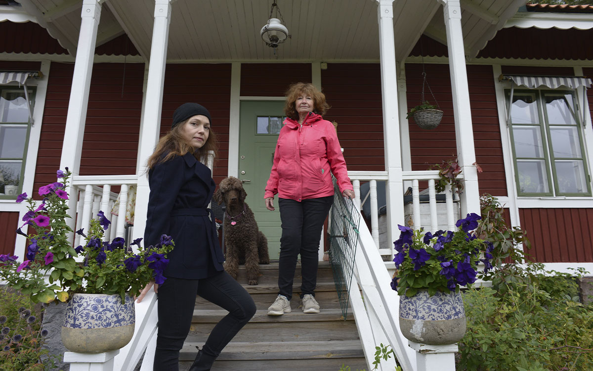 Två kvinnor och en storpudel på trappan till kulturvillan