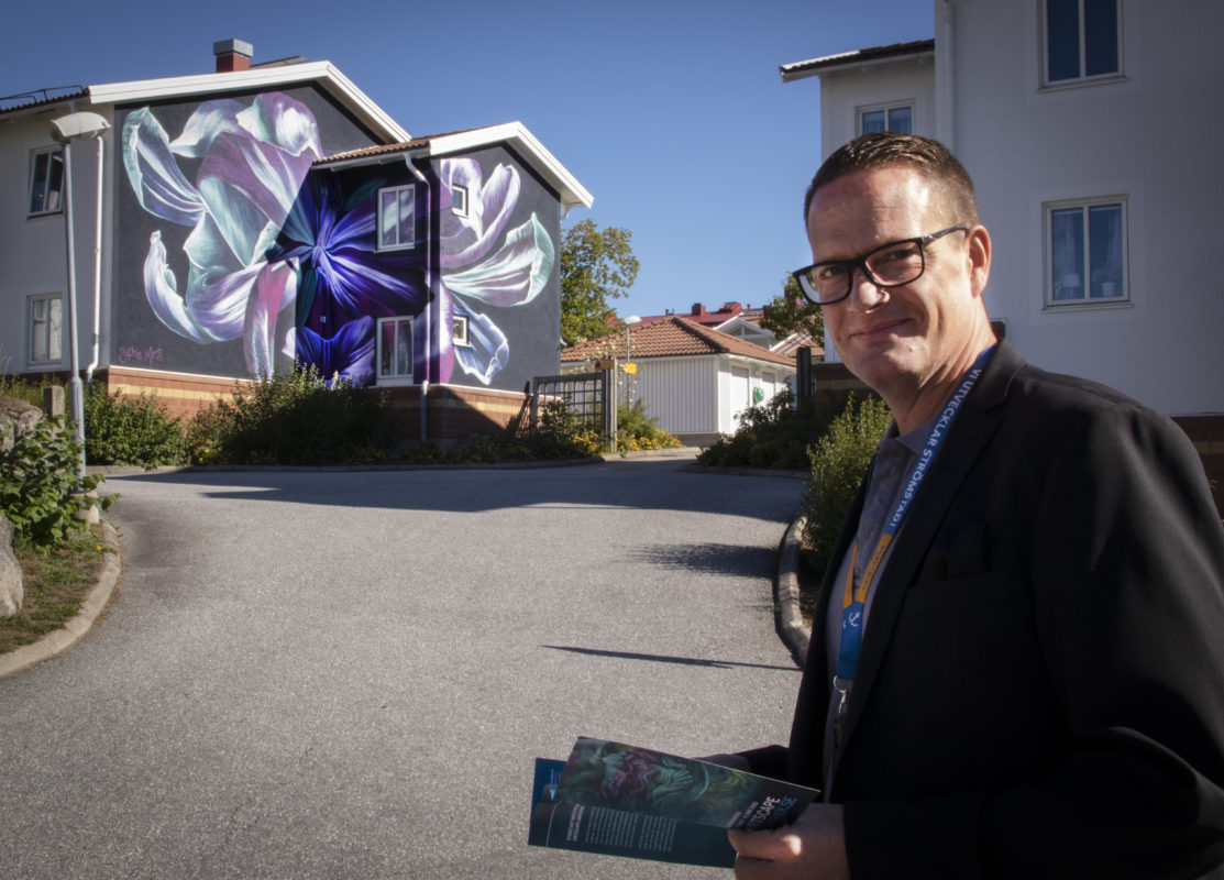 Strömstadsbyggens vd Tobias Kristiansson framför Sophie Mess konstverk på Södra Kyrkogatan 5. 