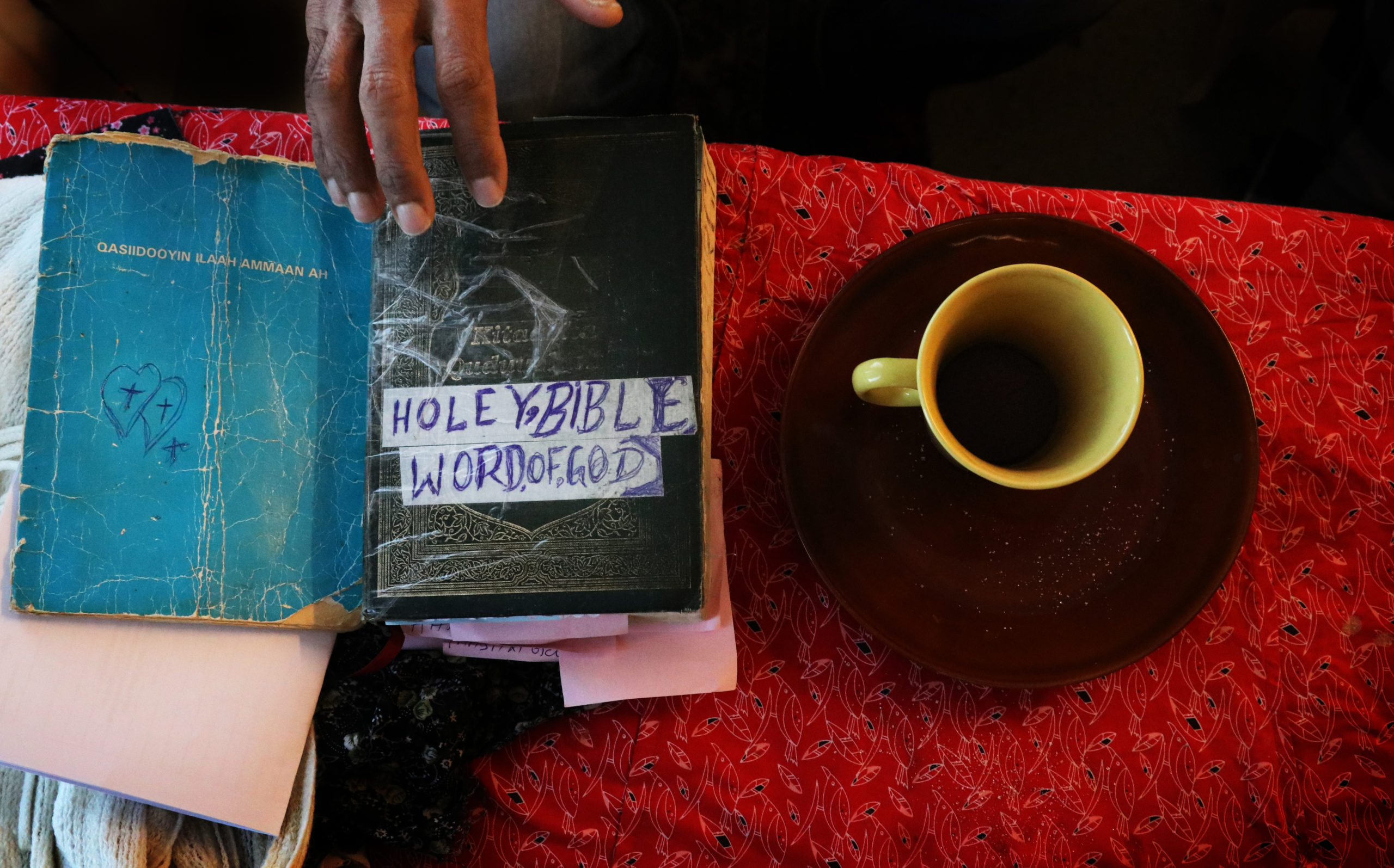 En kaffekopp och två böcker på ett bord med röd duk.