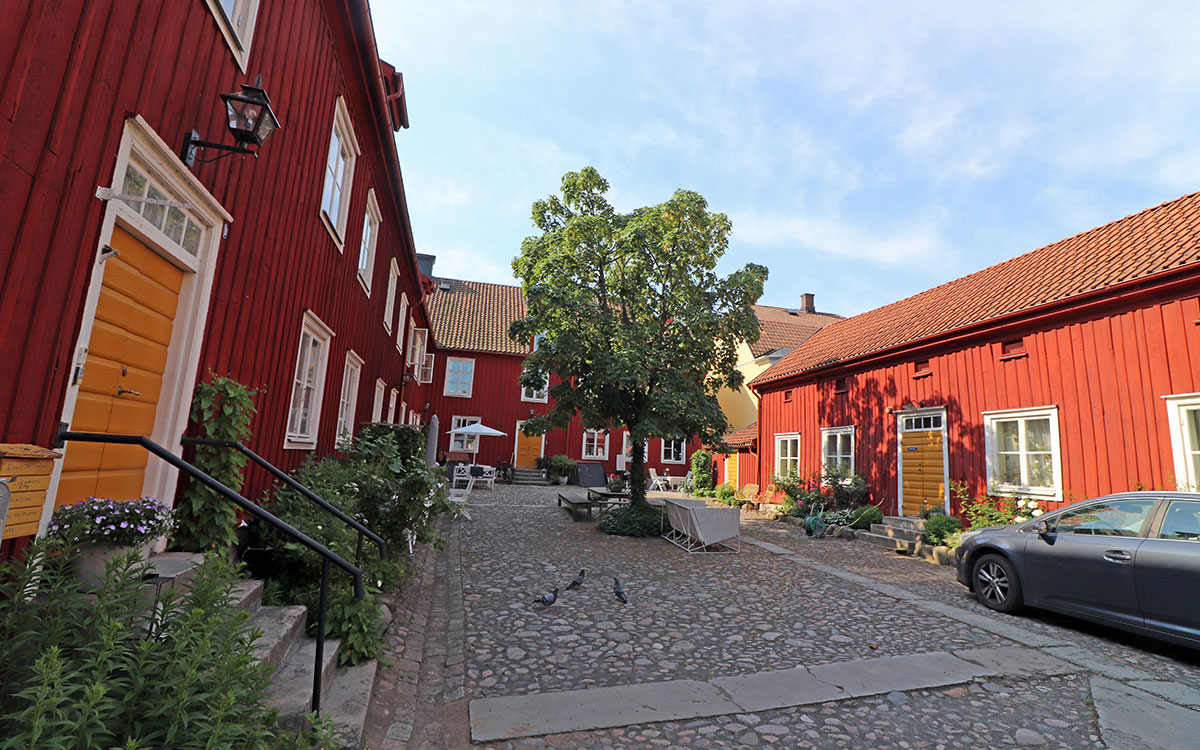 Hus med röda fasader runt en stenlagd innergård.