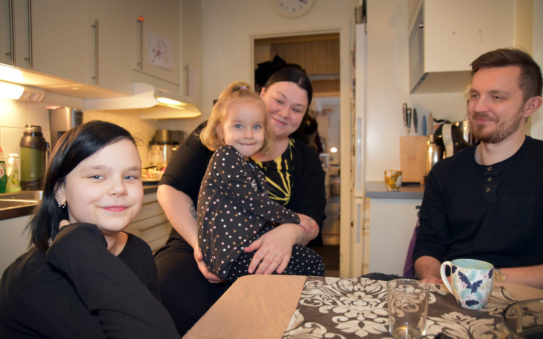 En glad familj runt köksbordet. Mamma, pappa och två barn.