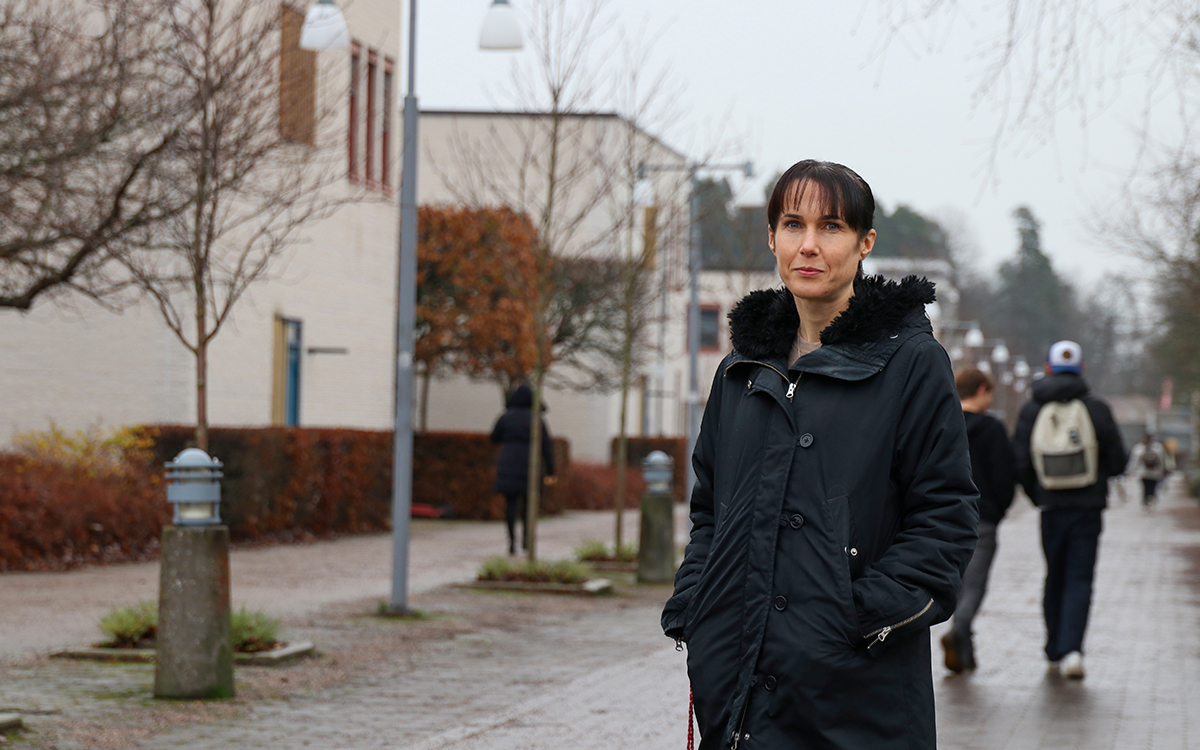 Ida Flink, som berättar om varför vi bråkar i tvättstugan, står i en gång på universitet. I bakgrunden syns två studenter gå.