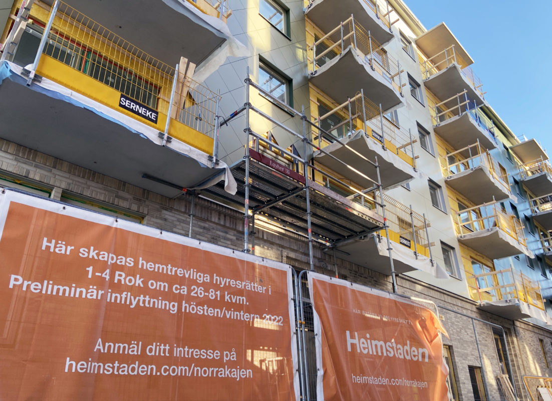 Byggställningar reser sig mot fasaden. Ett anslag berättar om de nya lägenheter som håller på att ta form.