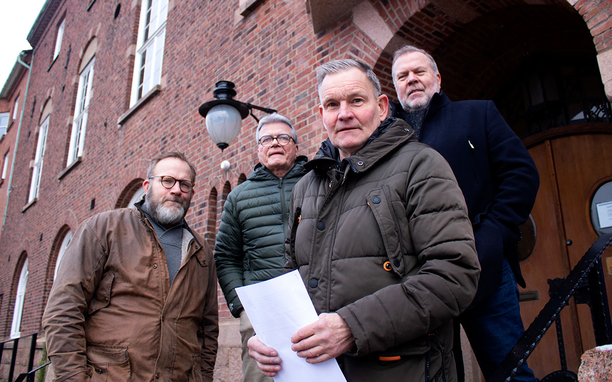 Fyra män står framför kommunhuset i Nässjö. En av dem håller papper i handen.