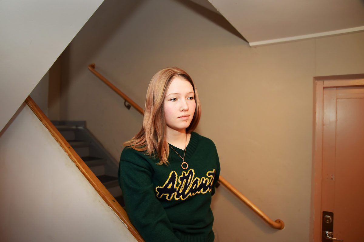 En tonårstjej står i trappen ner till en källare.