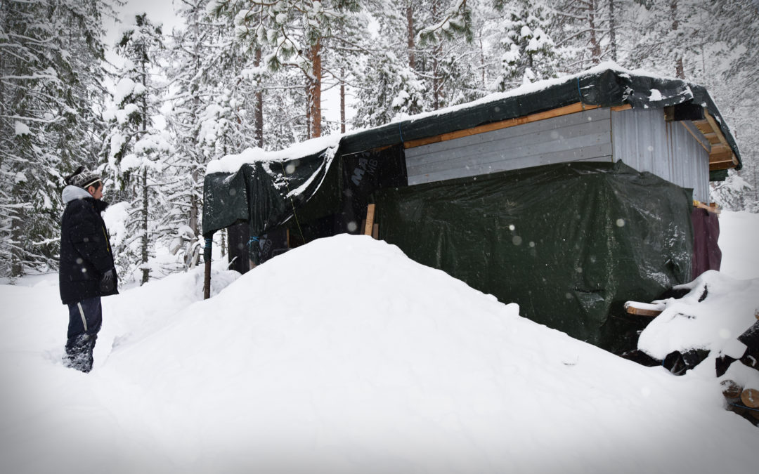 En medelålders man i ett snölandskap utanför en hemmasnickrad variant av koja.