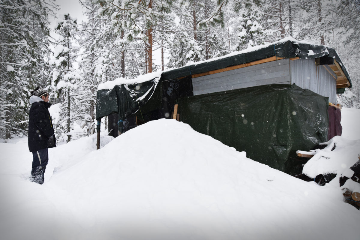 En medelålders man i ett snölandskap utanför en hemmasnickrad variant av koja.