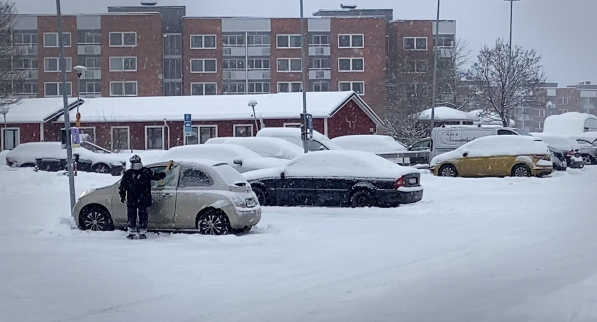 En man som sopar bort snön från en bil.