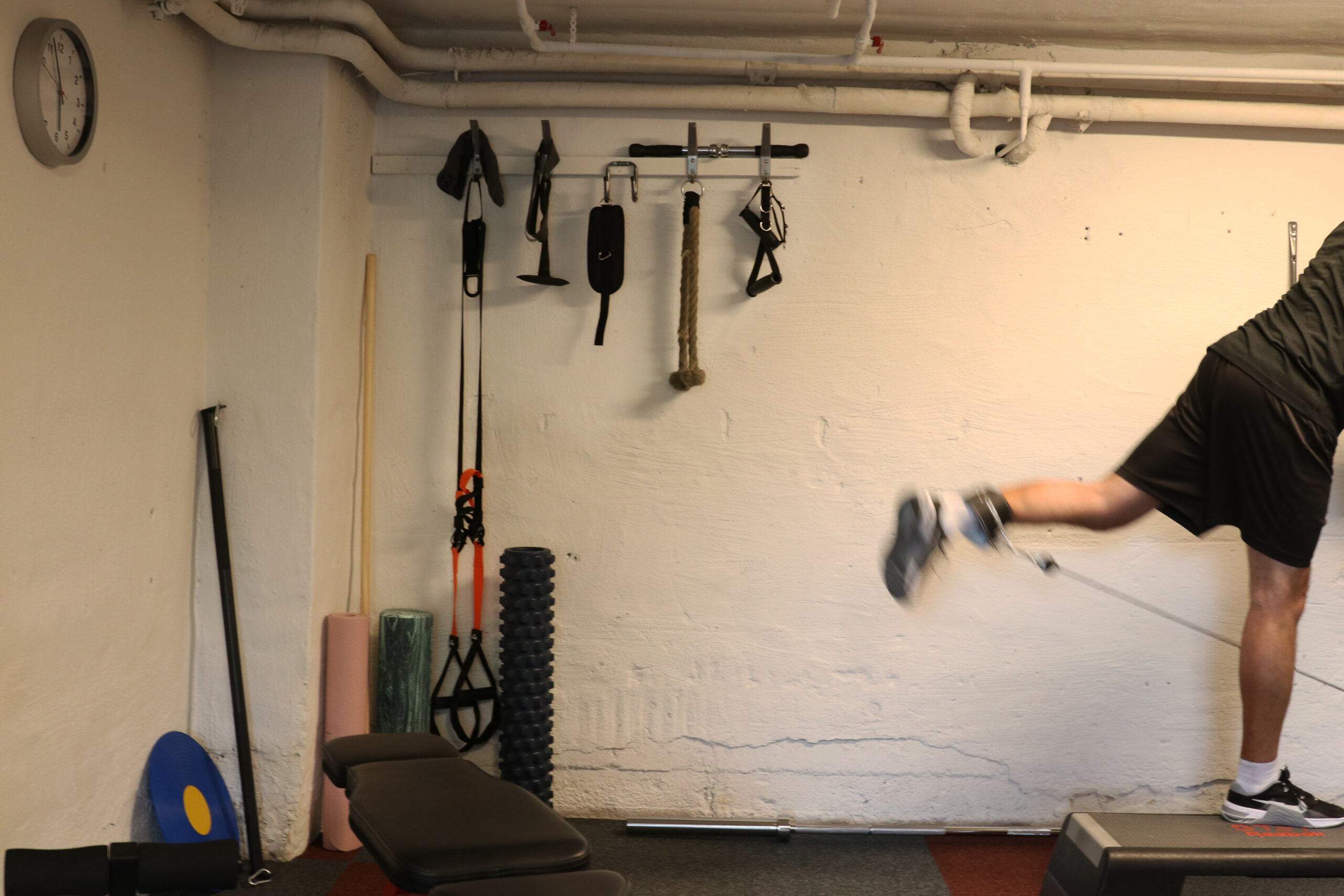 Ett ben i rörelse framför en vägg med träningsredskap.