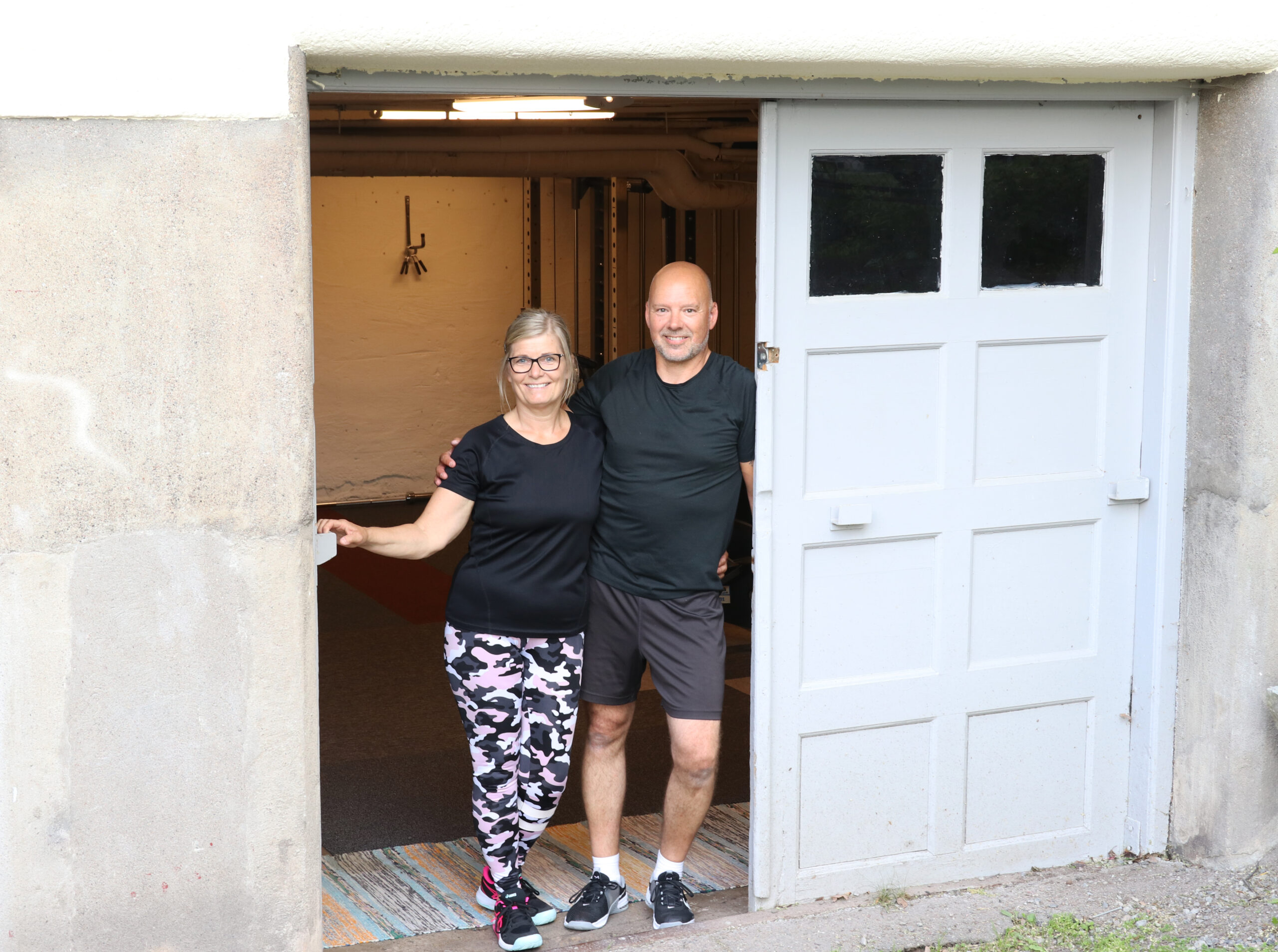 En kvinna och en man står i dörren till ett garage.