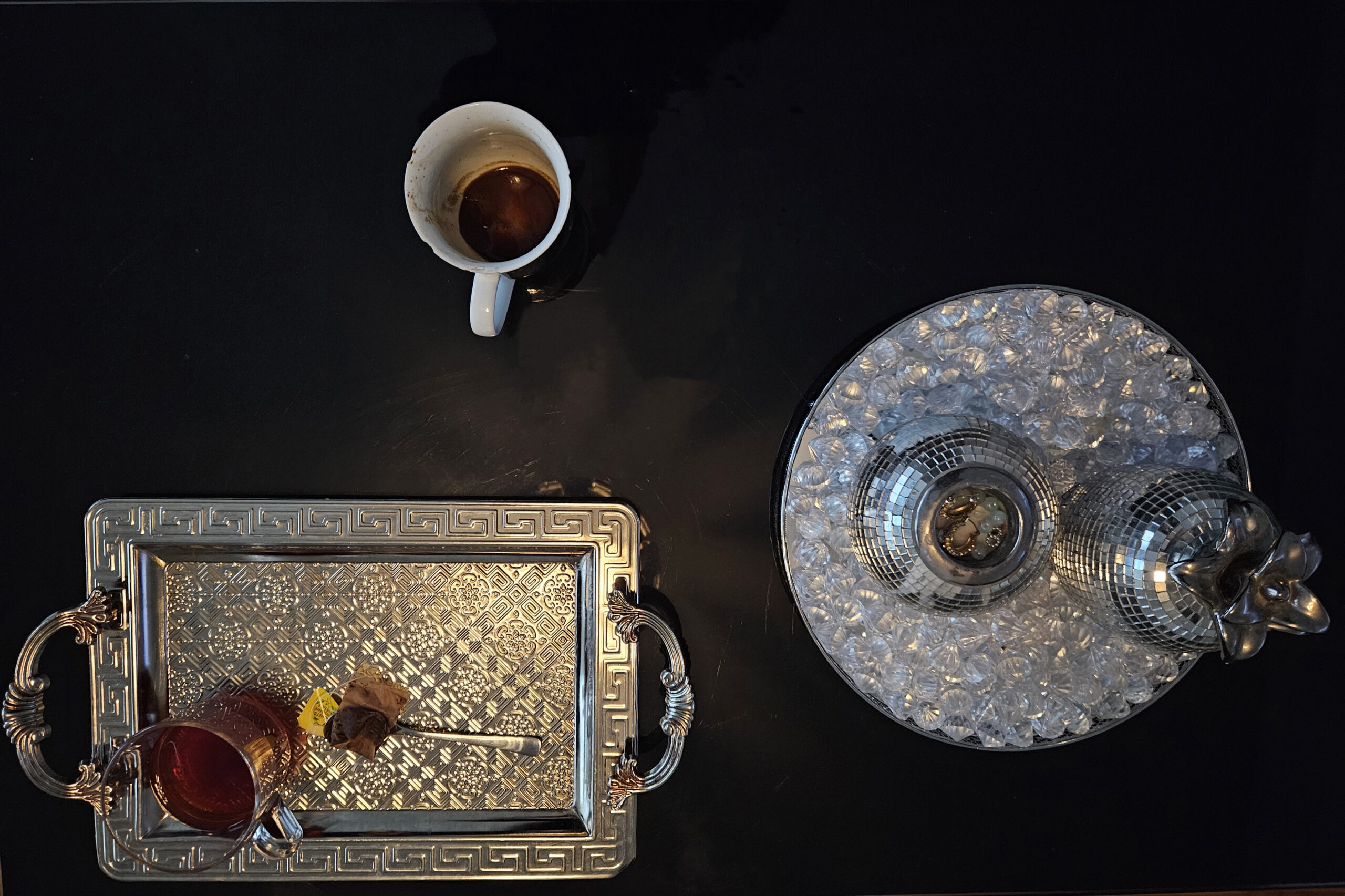 En silverbricka med te och kaffekopp på ett svart bord.