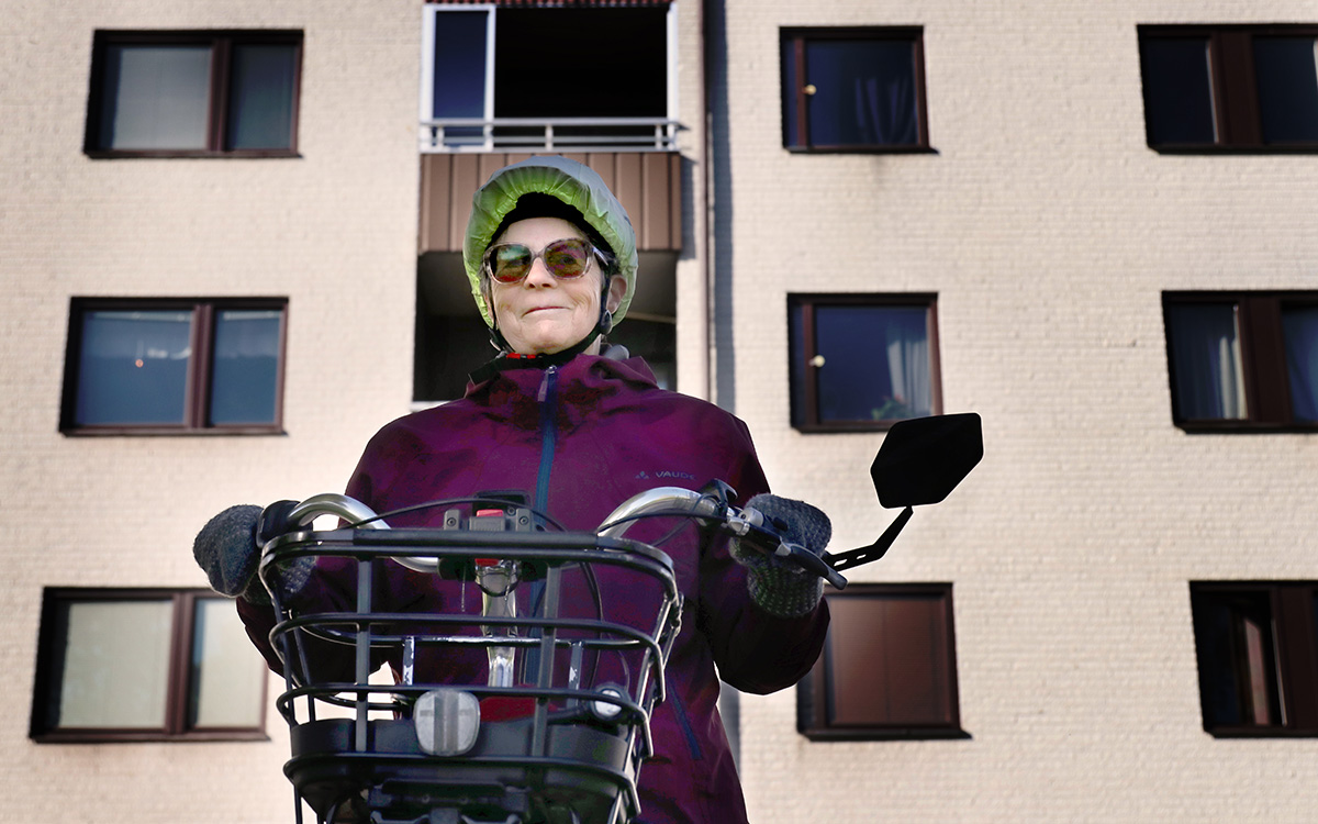 Dorothee med sin cykel i kvarteret där hon bor. I bakgrunden syns ett hus.