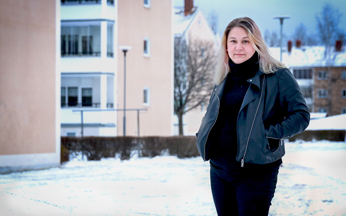 Cim Johansson intervjuades om att Tunabyggen stämmer sina hyresgäster i hög grad. Här syns hon i bostadsområdet Bullermyren. Hon står med händerna i en öppen jacka. På marken ligger snö.