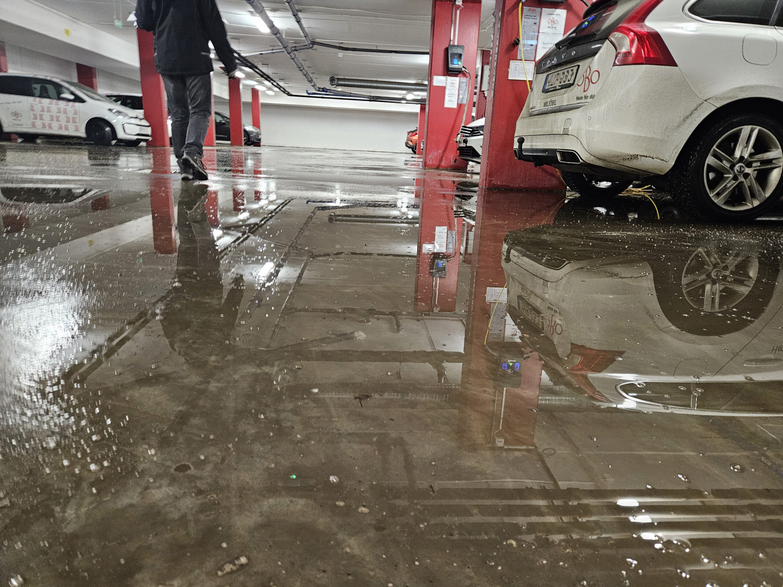 Ett garage där en person som går bortåt reflekteras i det våta golvet.