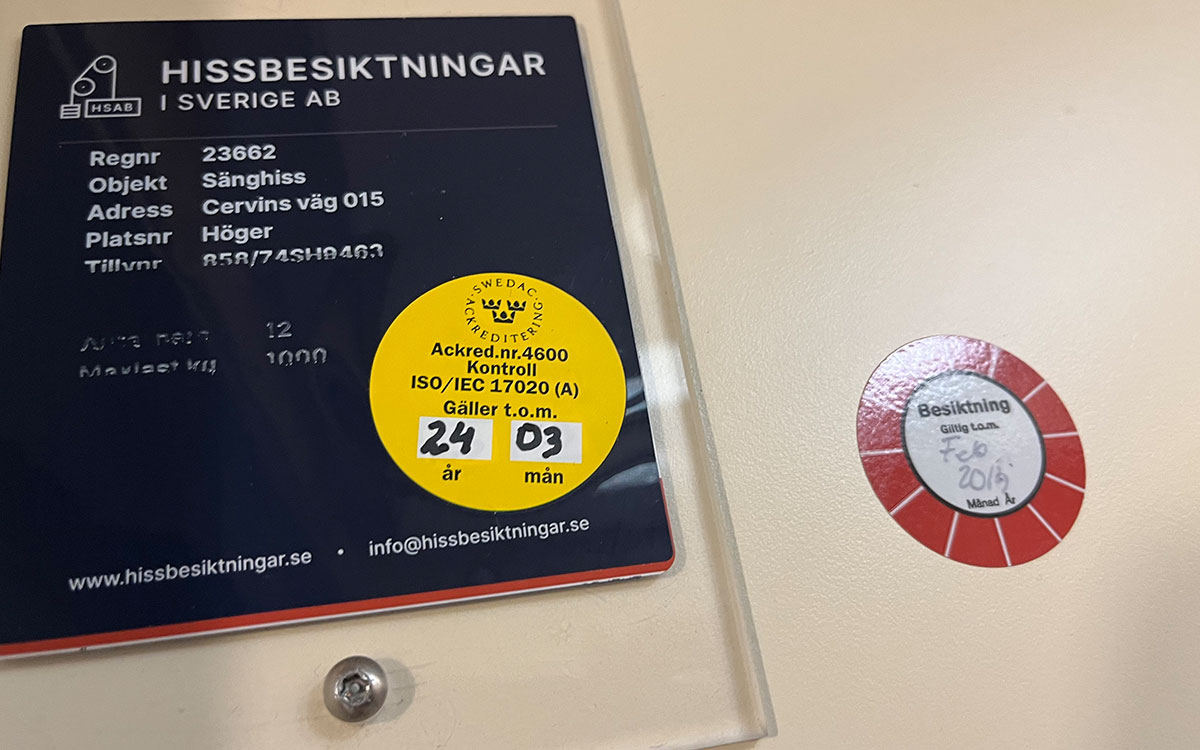 Kontrollera hissen. Bilden visar registreringsskylt och kontrollmärken.