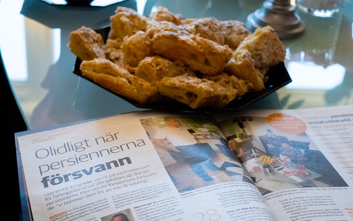 Ett kakfat med kakor och ett exemplar av tidningen Hem & Hyra som ligger på ett bord.