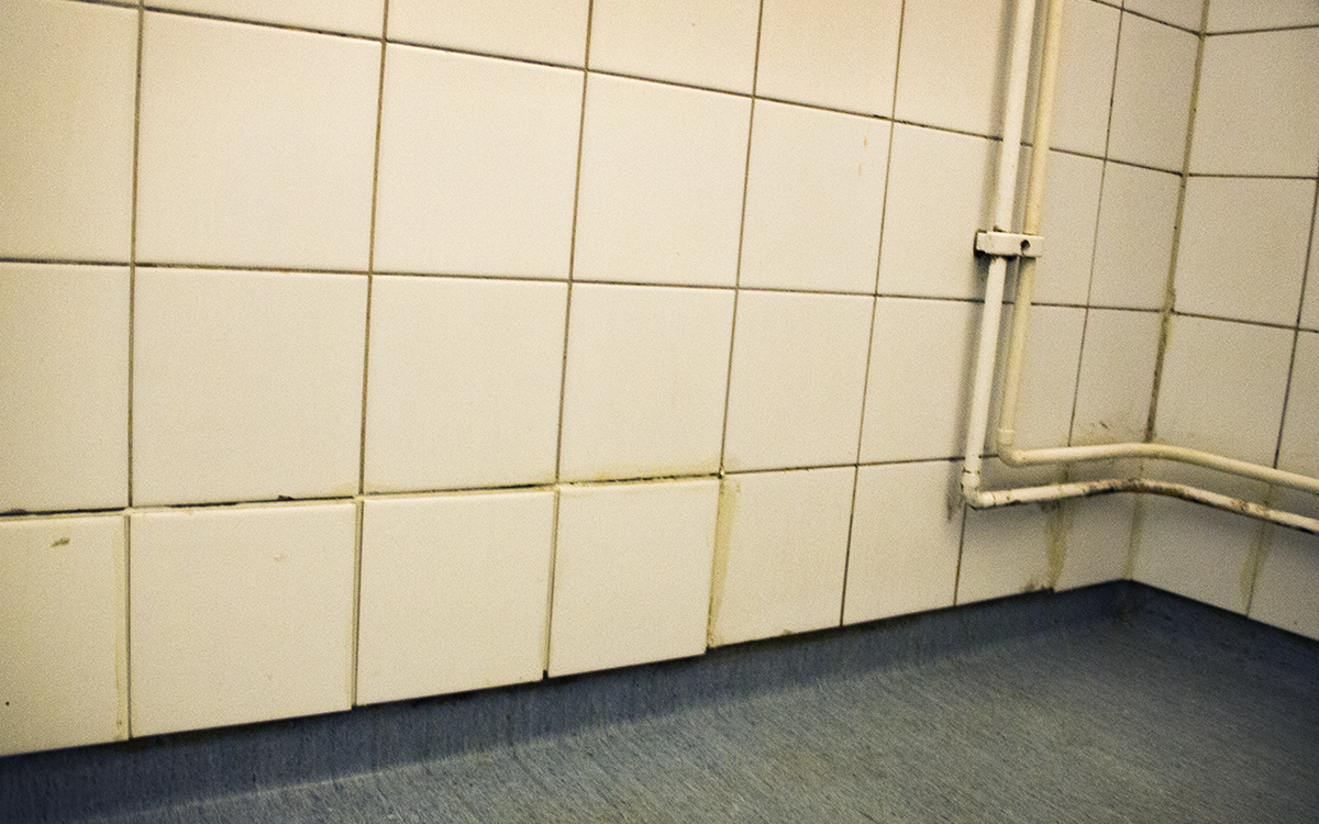 Dåligt fastsatta vita kakelplattor närmast den grå plastmattan på golvet i ett duschutrymme, AB-hem får kritik av hyresgäster på flera orter för brister i lägenheterna.