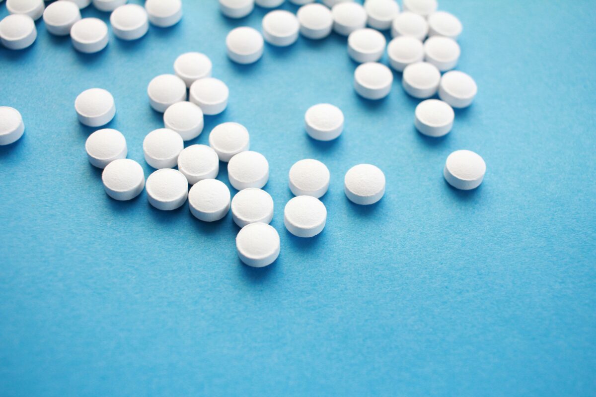 Bild på uthällda tabletter på blått underlag.