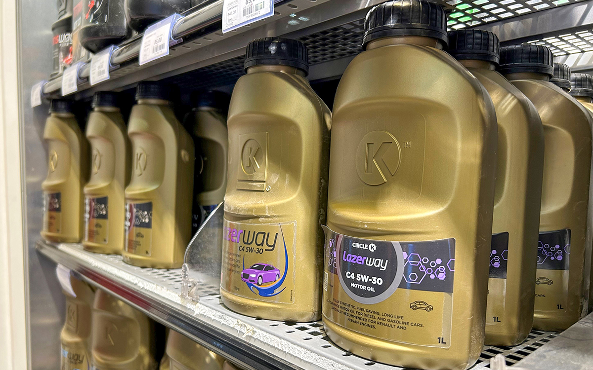 Guldgula flaskor med motorolja som står på en hylla i en bensinmack.