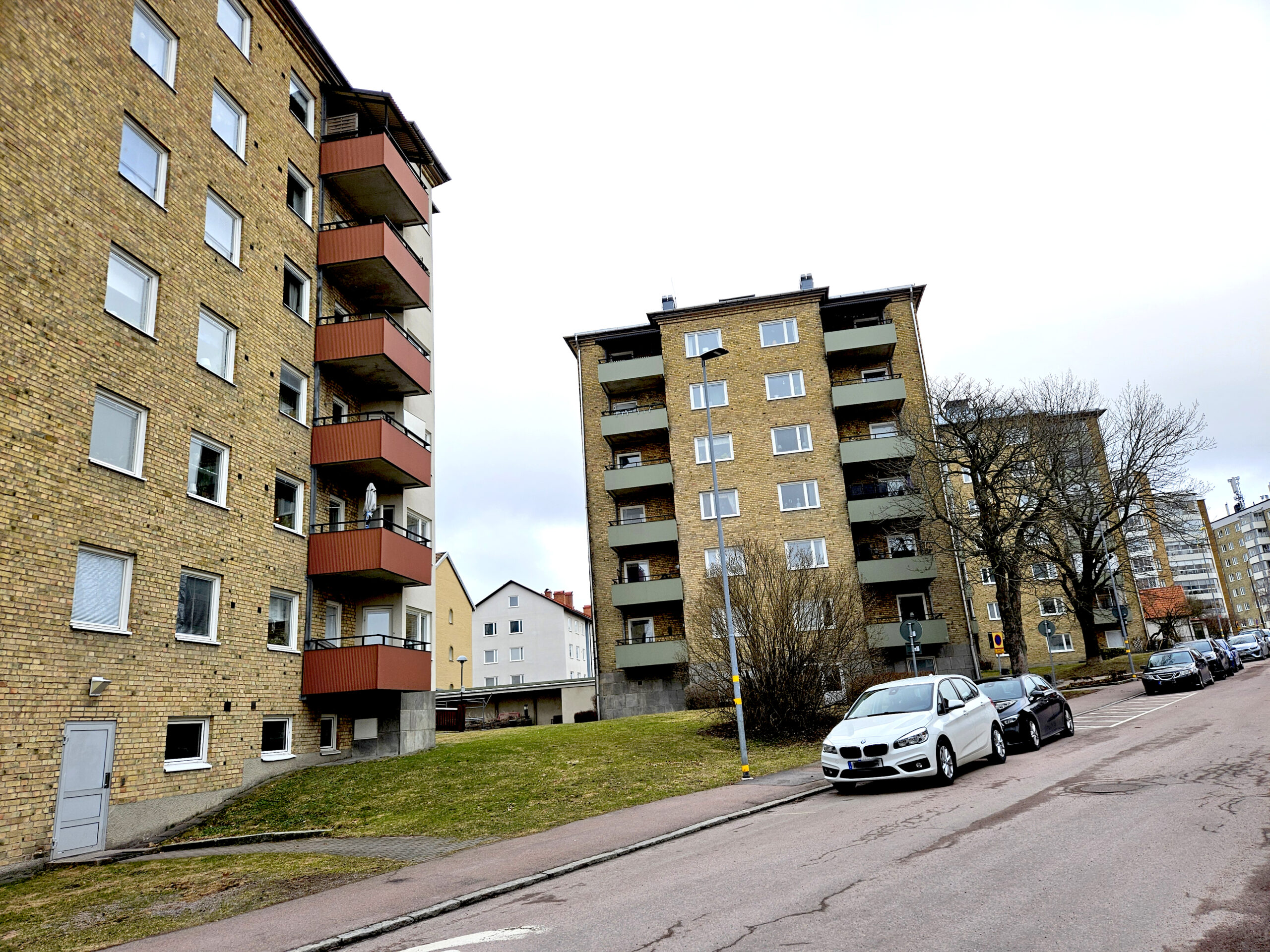 Tre gula tegelhus efter en gata med några bilar.