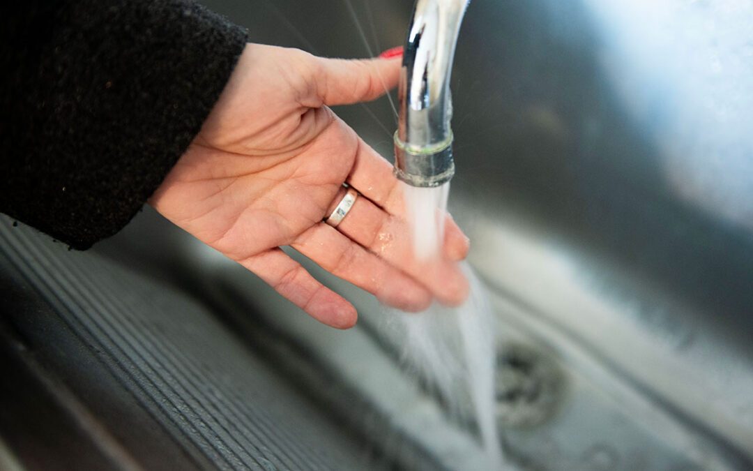 Hand som känner på rinnande vatten.