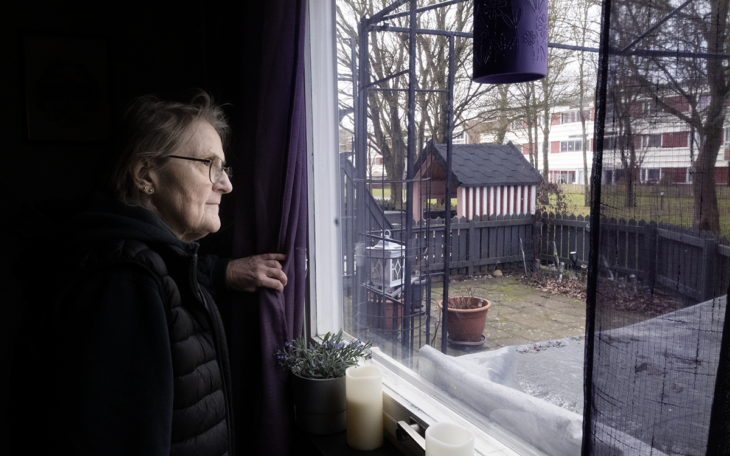 En kvinna som tittar ut från ett fönster.