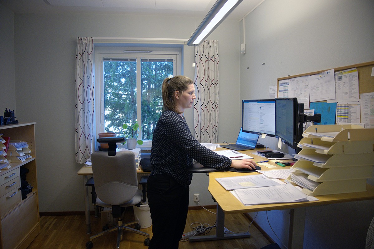Kvinna som står vid ett skrivbord med en datorskärm.